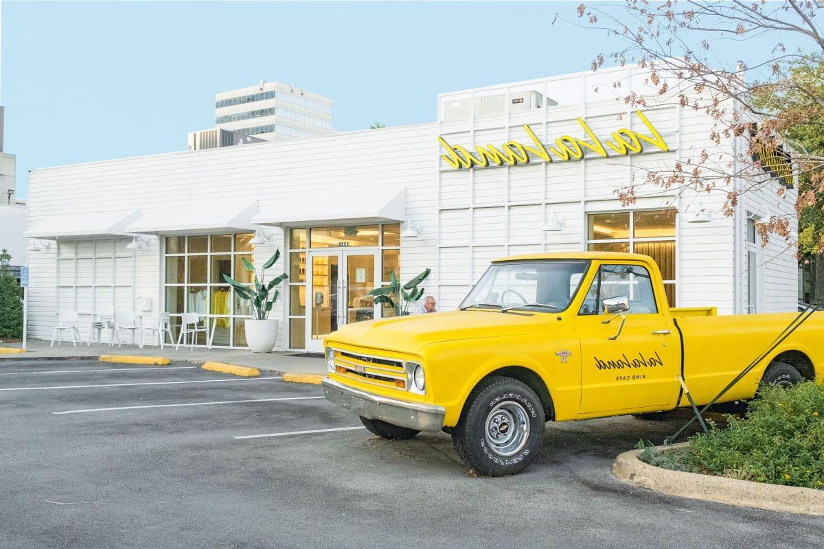 Photo of a bright yellow truck parked in front of a La La Land Kind Cafe