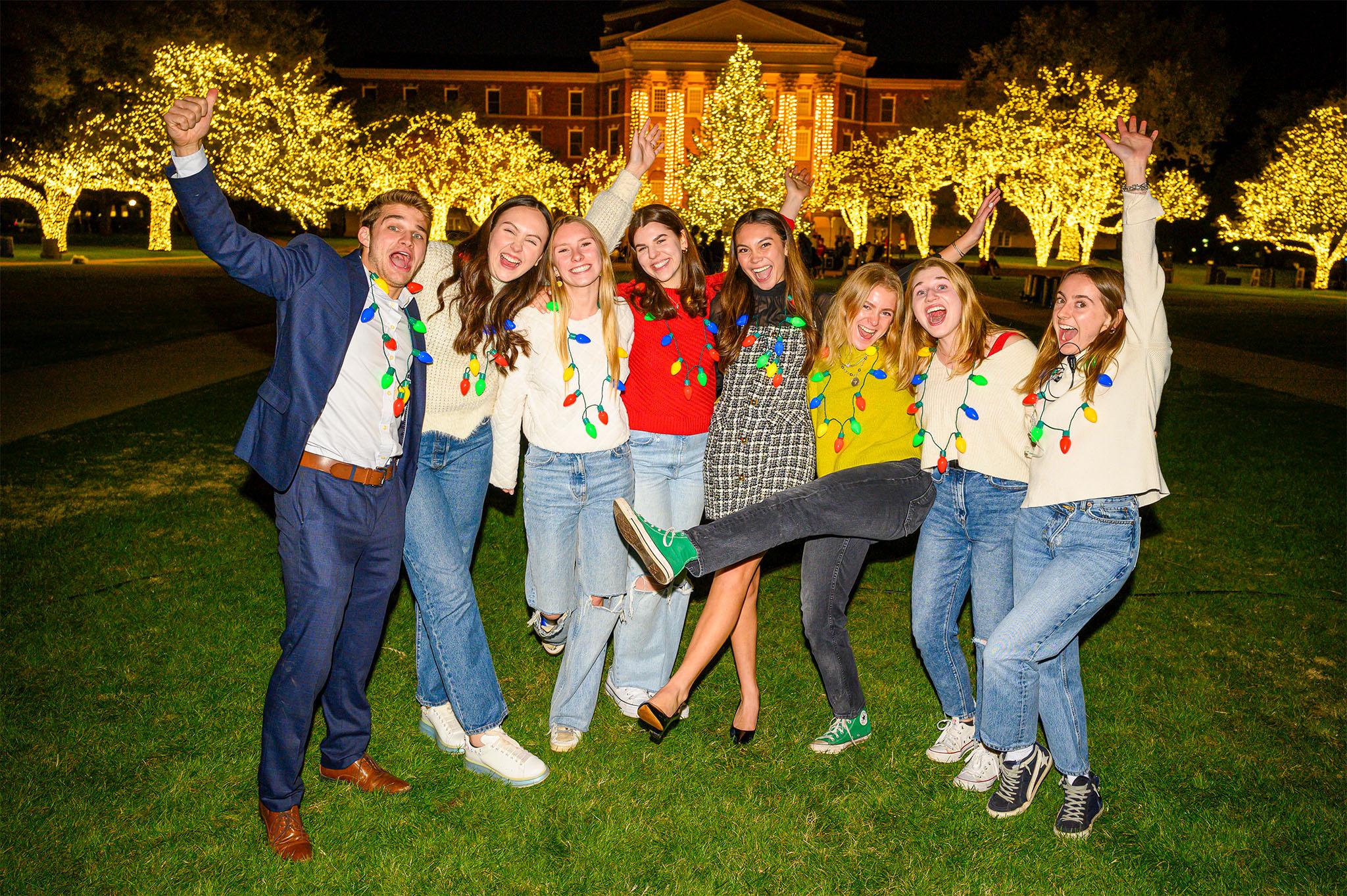 eight students celebration on dallas hall lawn in front of christmas tree at celebration of lights