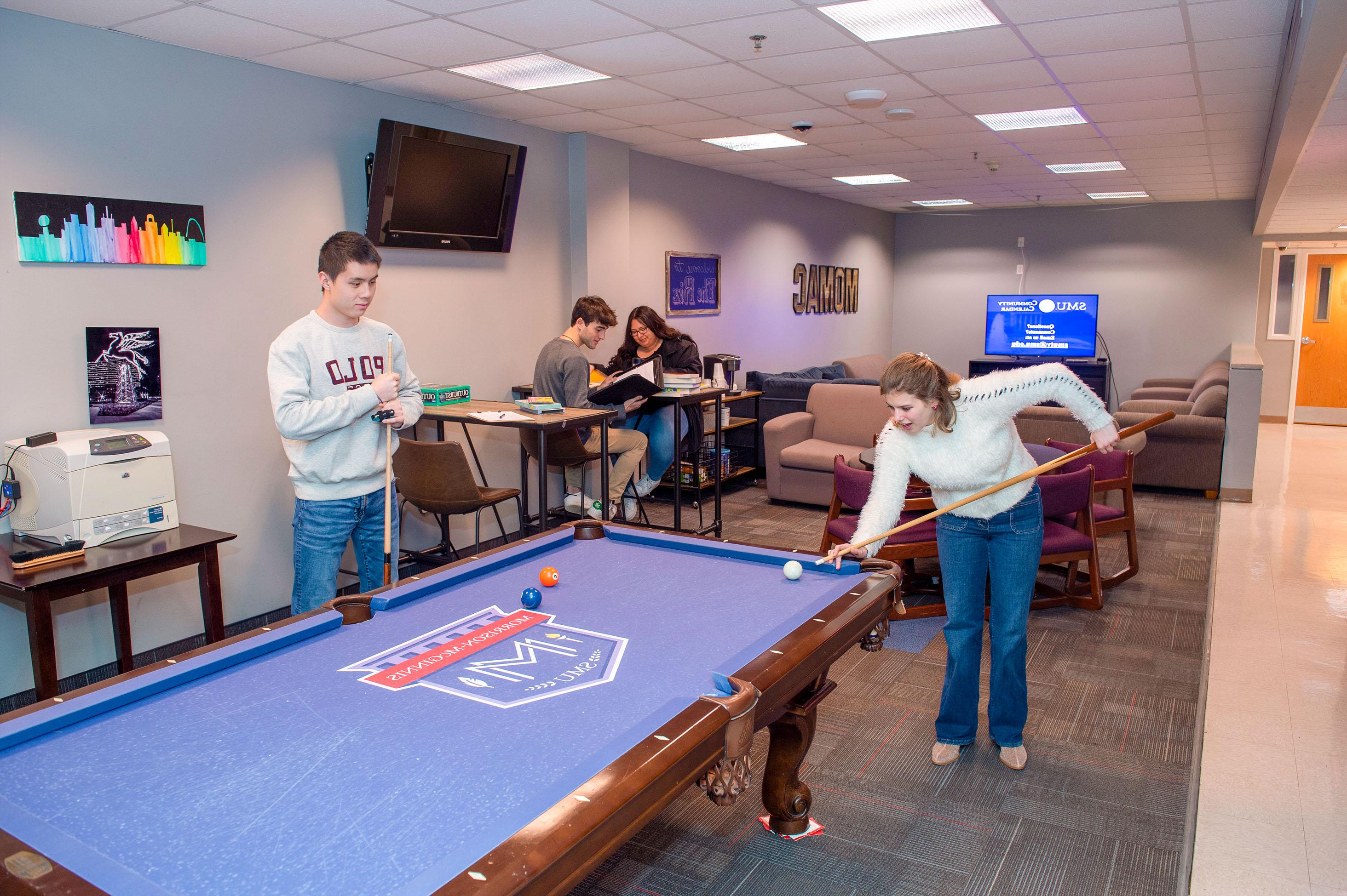 two students playing pool and two students sitting at a table in Morrison-McGinnis Commons